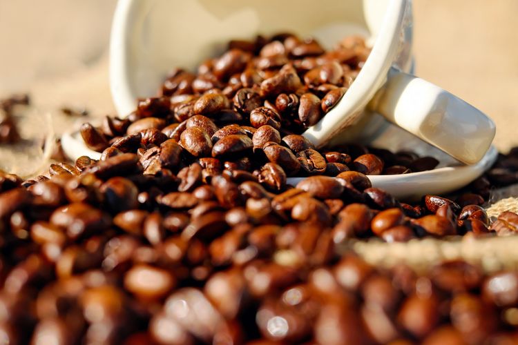 View of coffee beans spilling from cup
