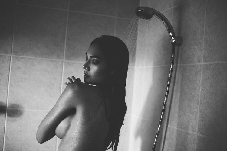 Seductive woman taking shower in bathtub