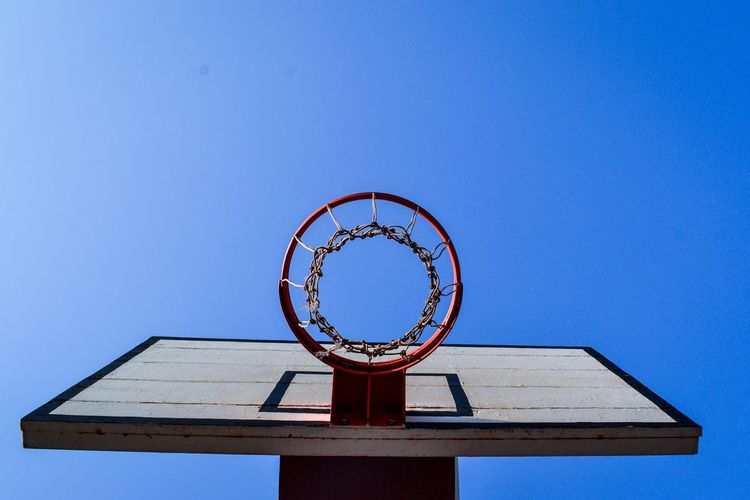 Directly below shot of basketball hoop against clear blue sky