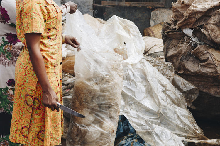 Midsection of people holding garbage bags