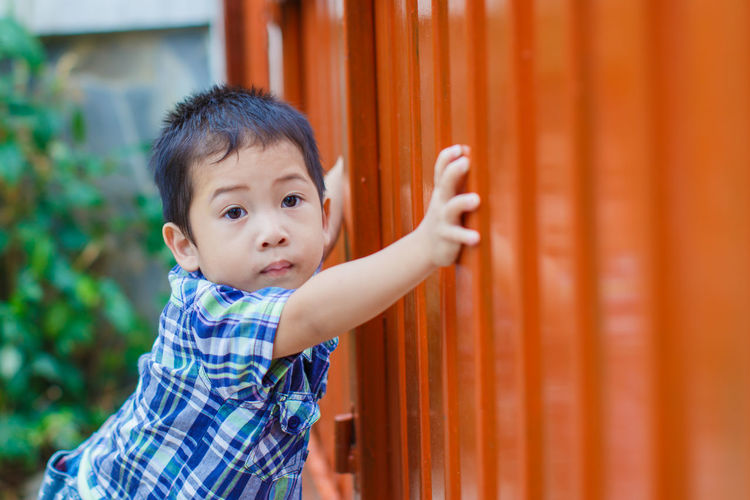Portrait of boy standing by gate