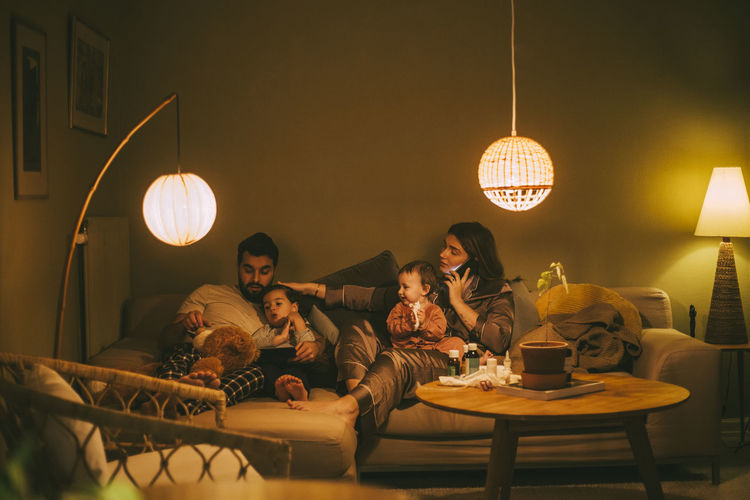 Parents sitting with children in living room at night
