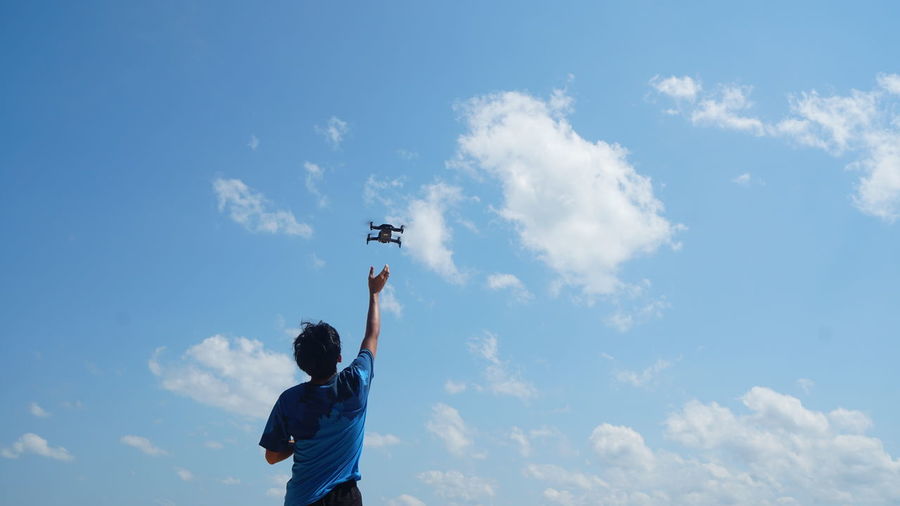 Low angle view of boy flying against sky