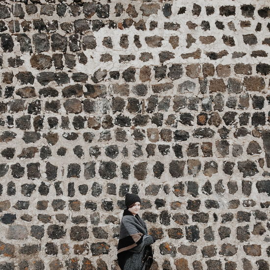 Young woman in front of stone wall