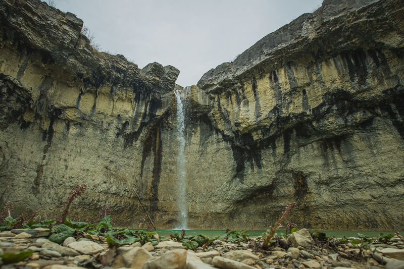 Scenic view of waterfall amidst rock formations against sky