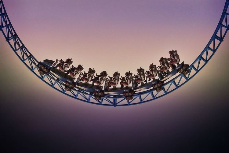 Low angle view of people on roller coaster against sky