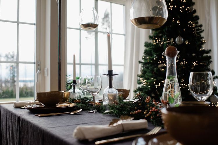 Tall lit candle on a decorated festive dinner table at christmas