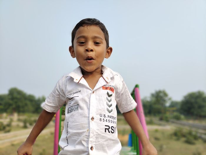 Portrait of boy standing against sky