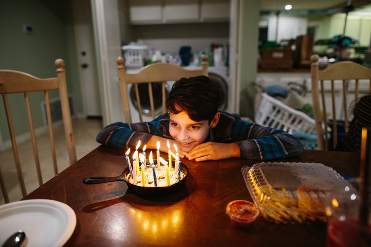 Boy smiles at the candles on his cast iron pan birthday cake person