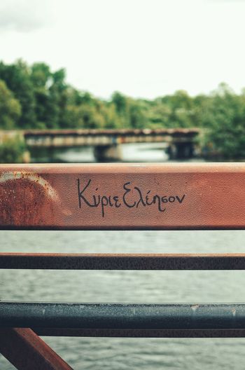 Close-up of text on railing against sky
