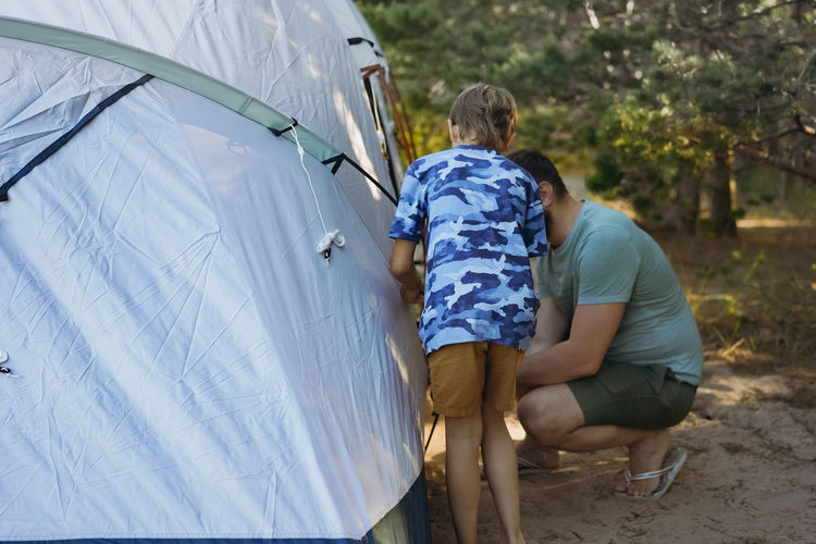 Cute little caucasian boy helping to put up a tent. family camping concept