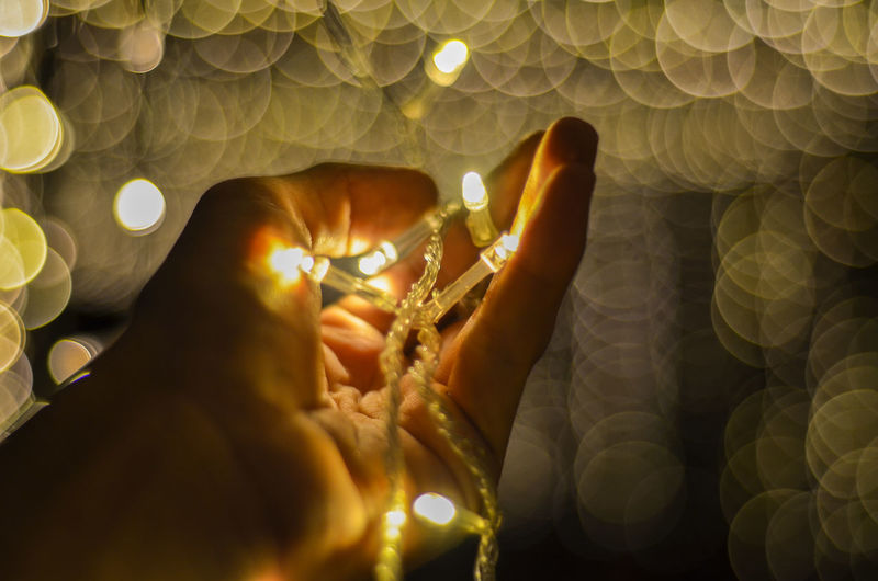 Close-up of hand holding illuminated string light