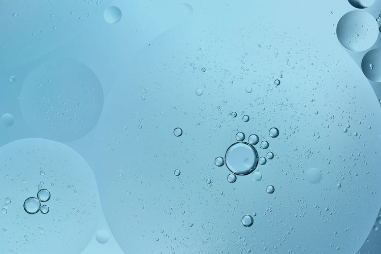 Oil drop floating or cosmetic liquid serum on the water blue bubbles background