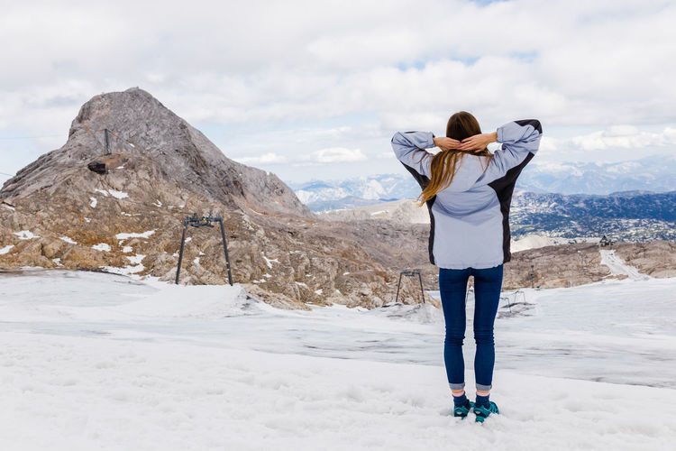 Rear view of woman standing on snow covered mountain
