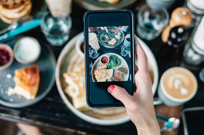 Cropped hand of woman photographing food served on table