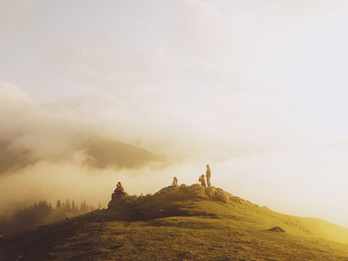 People on mountain against sky during foggy weather