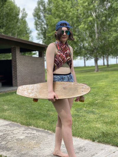 Teen girl holding skateboard in nature