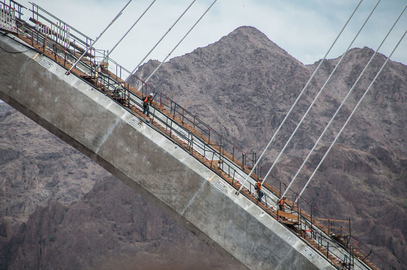 Workers on mike o callaghan pat tillman memorial bridge against mountains