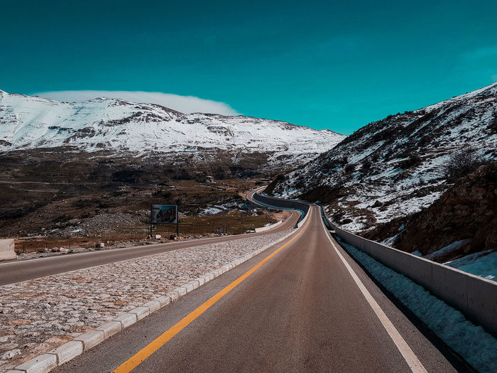 Road by mountains against clear blue sky