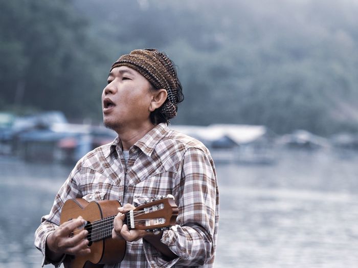 Man playing ukelele while standing outdoors
