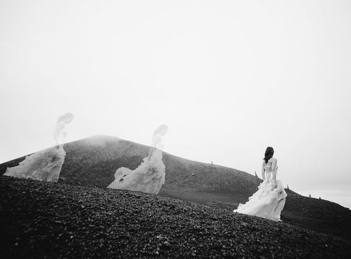 Multiple image of woman walking on mountain against clear sky