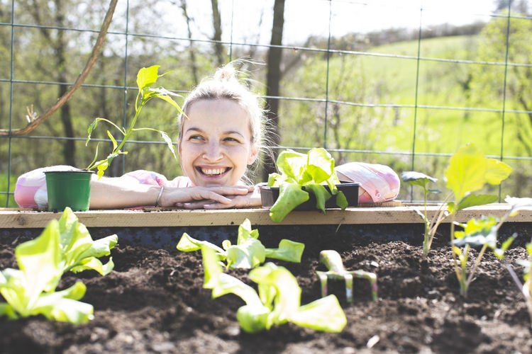 Smiling woman leaning on raised bed in yard