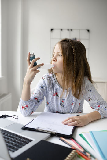 Portrait of young woman using mobile phone while sitting on table