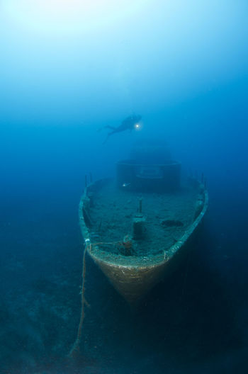 Person swimming over shipwreck undersea