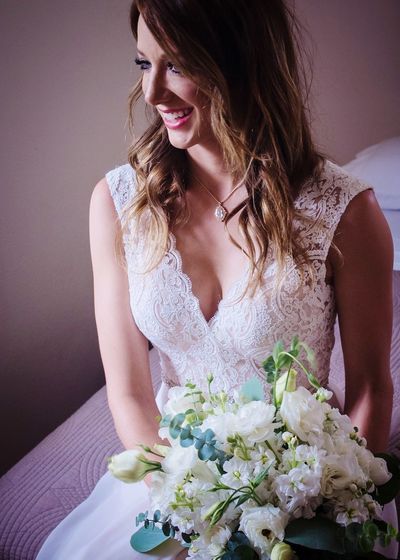 Close-up of young woman with flower bouquet sitting on bed
