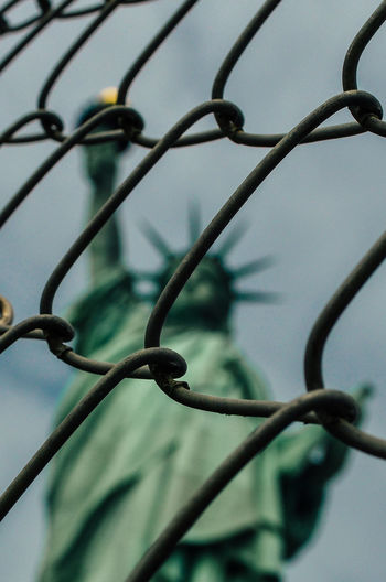 Close-up of chainlink fence against liberty statue 