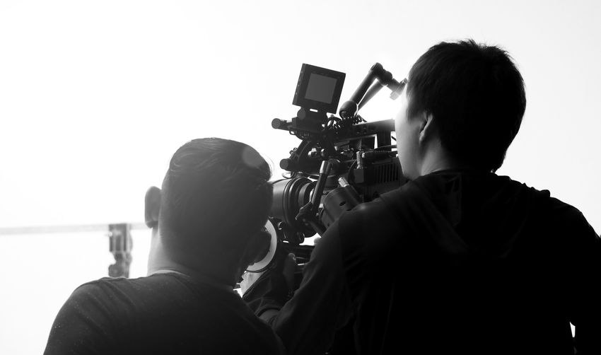 Rear view of operators using camera in studio