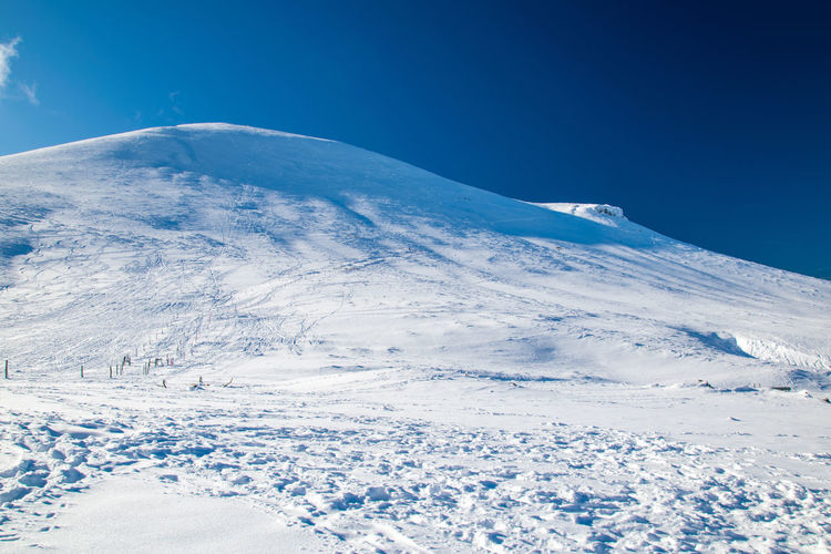 Scenic view of snowcapped mountain against blue sky