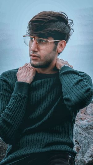 Young man looking away while sitting outdoors
