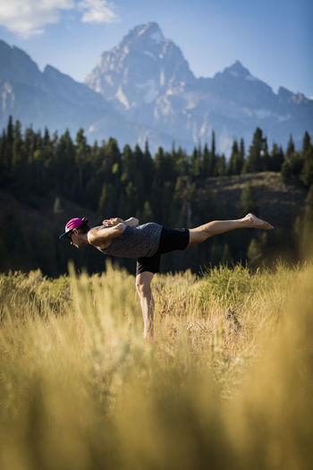Side view of man standing on one leg while practicing yoga on field at bridger-teton national forest
