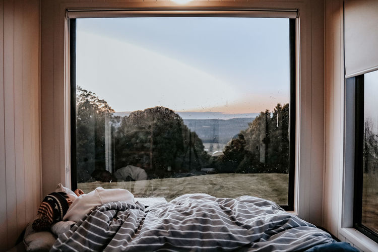 Rear view of woman sleeping on bed against landscape