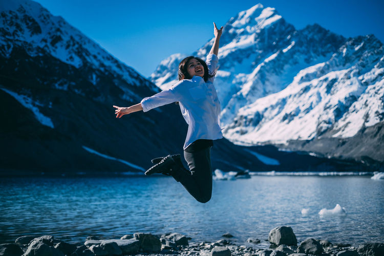 Young girl  jumping on mountain against sky