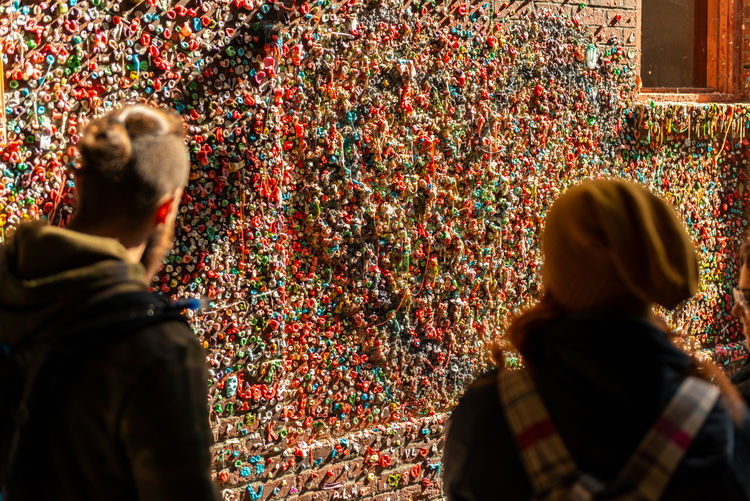 Rear view of people looking at gum wall