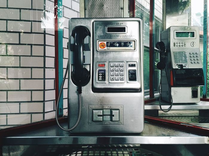 Close-up of pay phones seen through glass