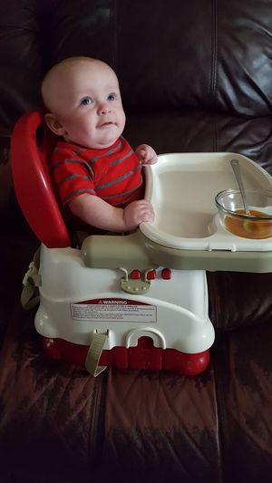 Cute baby sitting on high chair at home