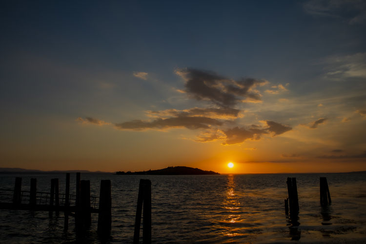 Scenic view of trasimeno lake against sky during sunset