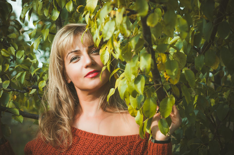 Portrait of young woman standing amidst branches