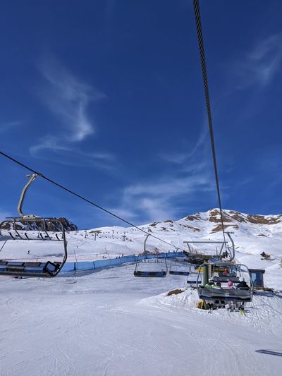 Ski lift on snow covered mountain against sky