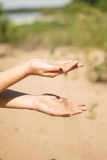 Close-up of woman hand on sand
