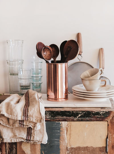 Kitchen utensils, glassware and dinnerware on rustic kitchen counter