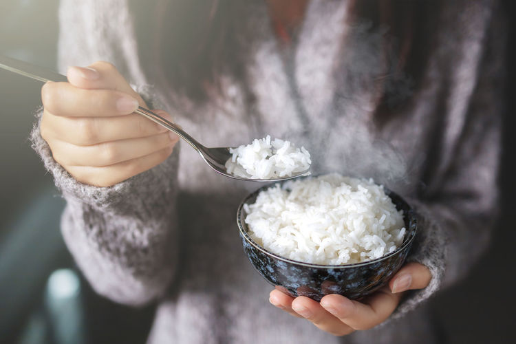 Midsection of woman holding rice in bowl