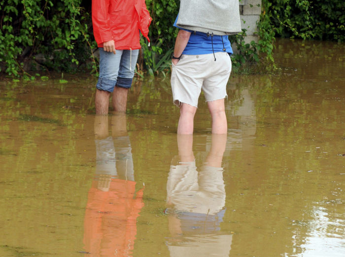 Midsection of people standing in floodwater