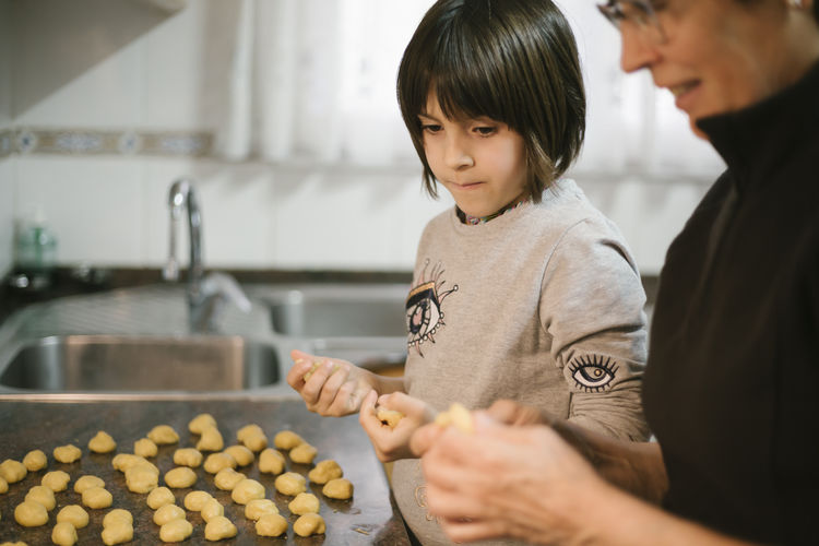 Little girl baking cookies at home with her grandma