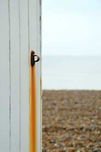 Close-up of rusty hook on beach hut against sky