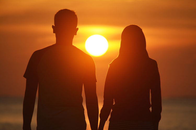 Rear view of couple at beach during sunset