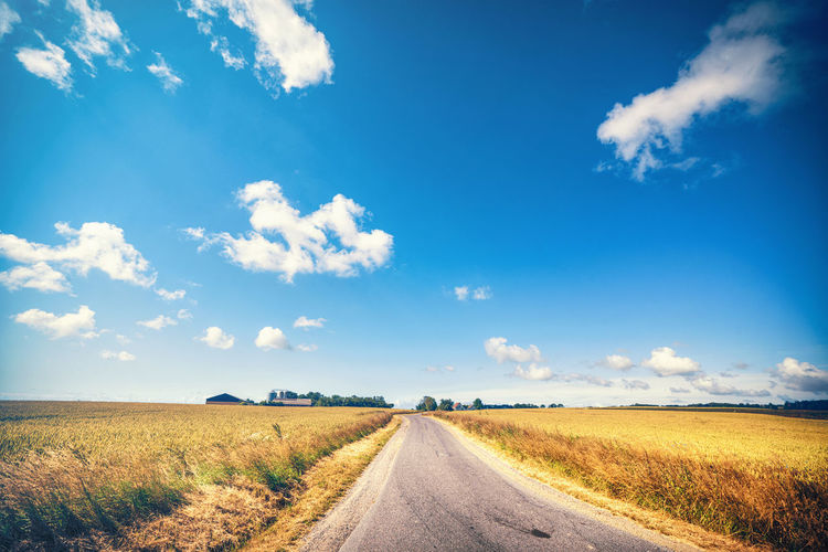 Road amidst field against sky